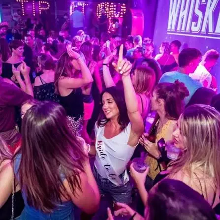 Bachelorette group dancing under pink and purple club lighting