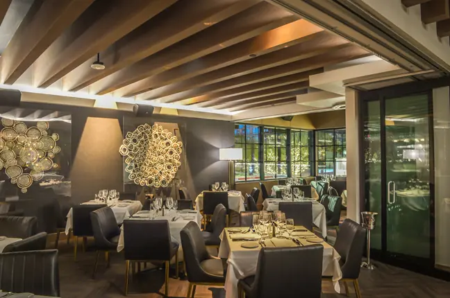 Intimate dining room with slatted ceiling and circular light sculptures
