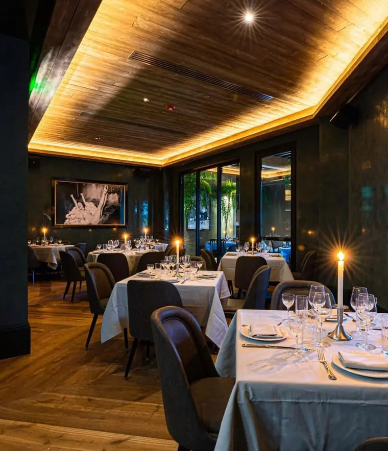 Candlelit dining room with white linen tables and dark walls
