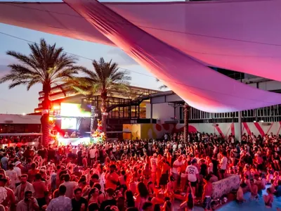Maya pool deck at dusk, crowd under shade sails