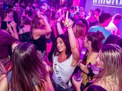 Crowd dancing under pink and purple club lighting